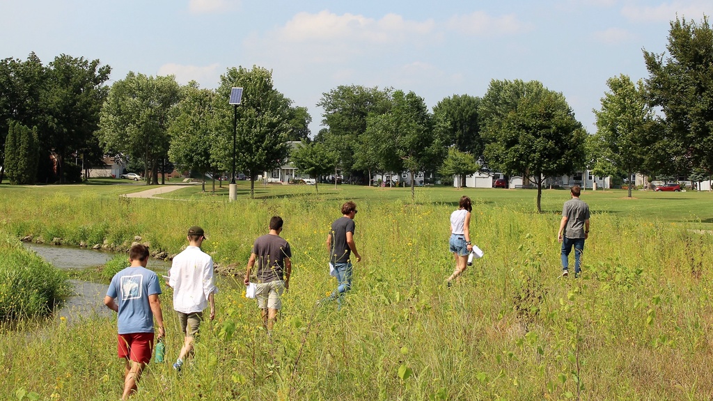 UI urban planning students walking through a field near Maquoketa, Iowa as part of their Field Problems community outreach course.